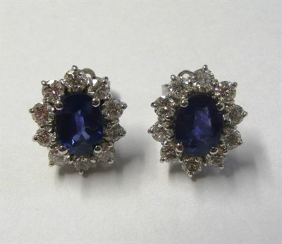 Lot 596 - A Pair of 18 Carat White Gold Sapphire and Diamond Cluster Earrings, each comprises an oval...