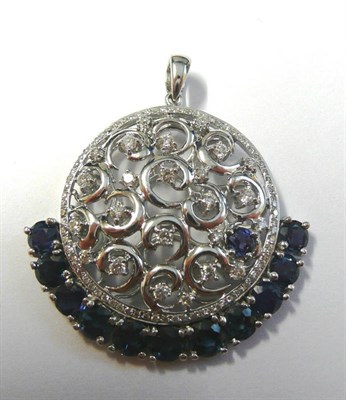 Lot 614 - An 18 Carat White Gold Sapphire and Diamond Pendant, the central openwork scrolling form set...