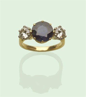 Lot 624 - An 18 Carat Gold Sapphire and Diamond Three Stone Ring, a round brilliant cut sapphire in a...