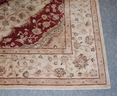 Lot 1071 - A machine made carpet of Oriental design, the brick red field of vines around a medallion...
