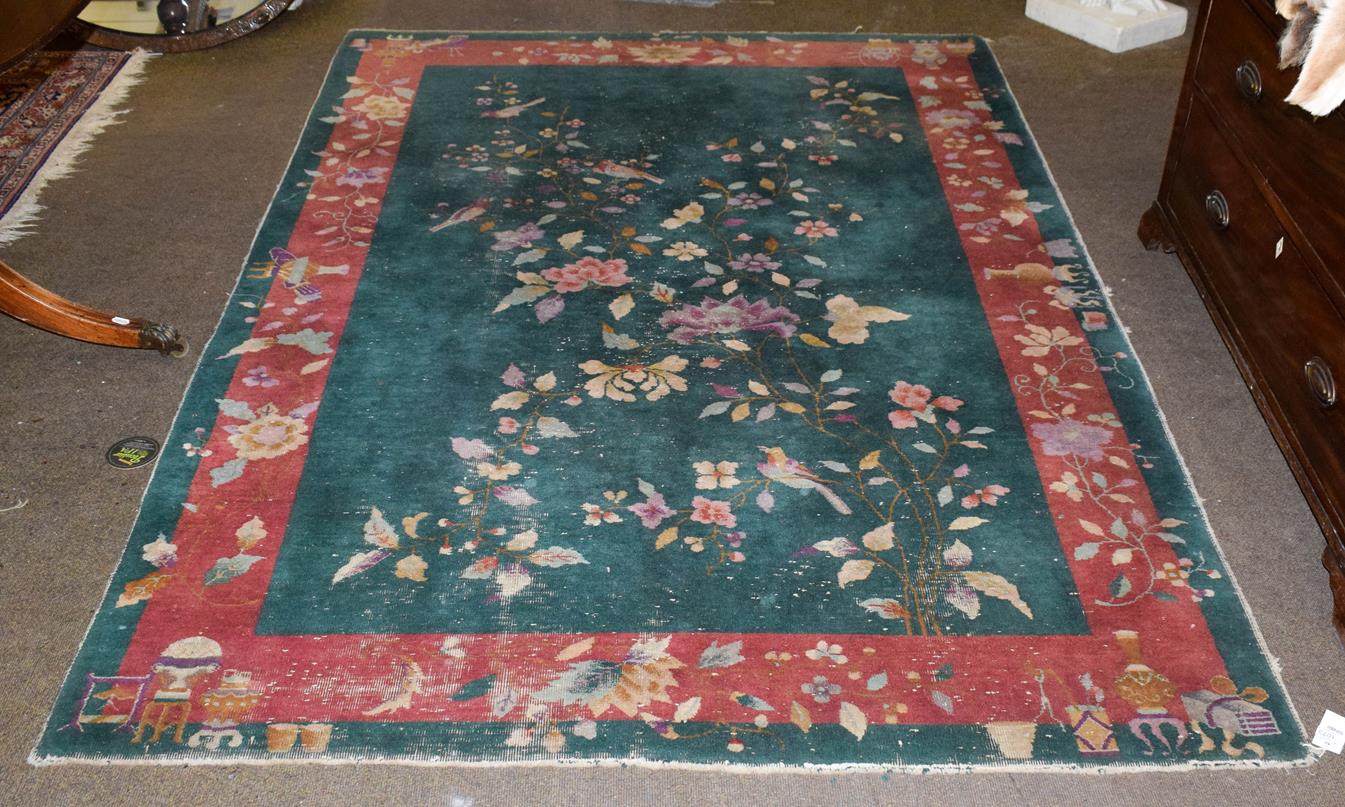 Lot 1073 - Chinese Art Deco rug, the emerald green field with a plant in flower enclosed by meandering...