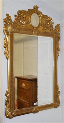 Lot 1149 - A gilt framed mirror surmounted by flowers and leaves, 78cm by 127cm