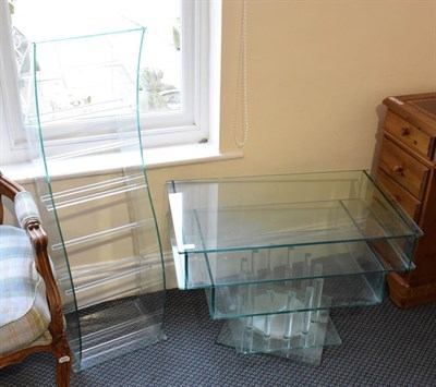 Lot 1166 - A modern glass serpentine formed open bookcase, 112cm high together with a matching revolving...