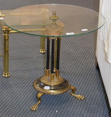 Lot 1188 - A gilt metal glass-topped table, the circular top raised on three patinated reeded supports and...
