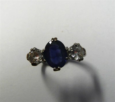 Lot 637 - A Sapphire and Diamond Three Stone Ring, the oval mixed cut sapphire flanked by a round...