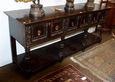 Lot 1197 - A 17th century style carved oak sideboard, with three panelled drawers and open bottom tier,...