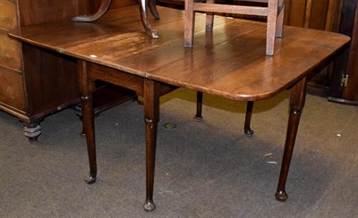 Lot 1221 - An 18th century oak gate-leg dining table on turned supports terminating on pad feet, 145cm by 118m