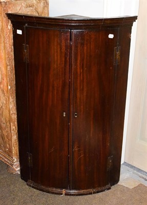 Lot 1298 - A George III bow front mahogany hanging corner cupboard, 71cm by 110cm