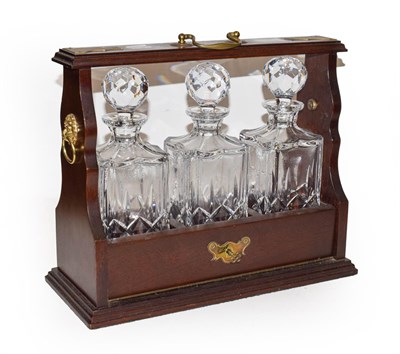 Lot 210 - A 20th century gold Tantalus with three heavy glass decanters with mahogany case with key