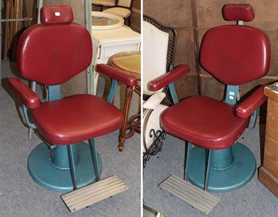 Lot 1075 - A pair of red leather and cast metal barbers chairs