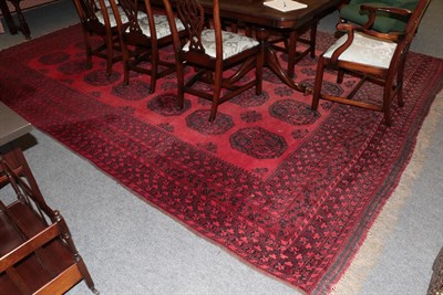 Lot 1128 - An Afghan Turkmen carpet, the crimson field with four rows of elephant foot guls enclosed by...