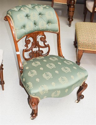 Lot 1136 - A Victorian Rosewood nursing chair with an open scrolling back upholstered in a green and gold...