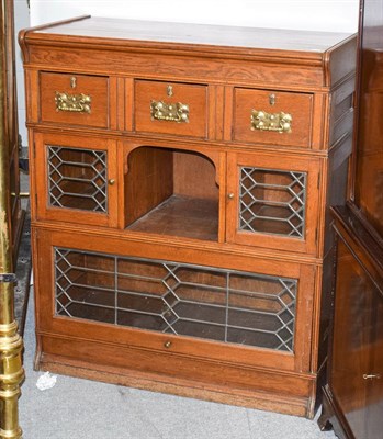 Lot 1197 - An early 20th century oak side cabinet in three sections, the upper section with three drawers...