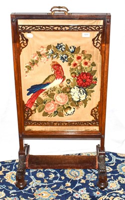 Lot 1211 - A Victorian glazed fret work decorated fire screen with a wool work panel depicting a parrot...