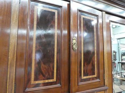 Lot 1268 - A Victorian crossbanded mahogany mirrored triple wardrobe with fitted interior and shaped pediment