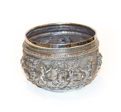 Lot 130 - A Burmese silver bowl, circular, the sides embossed with figures in high relief in landscapes,...
