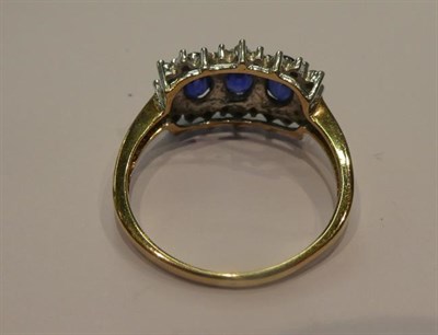 Lot 176 - A 9 carat gold sapphire and diamond cluster ring, three oval sapphires within a border of eight-cut