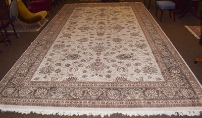 Lot 1151 - A large machine made carpet of oriental design, the cream field with an all over design of...