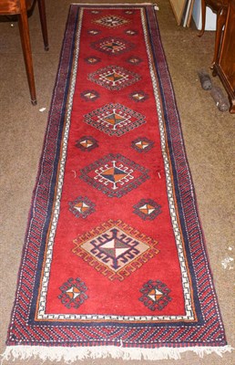 Lot 1152 - A Caucasian design runner, the blood red field with a column of latch hook guls enclosed by...