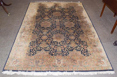 Lot 1153 - An Indian carpet, the indigo field with an all over floral design enclosed by meandering vine...