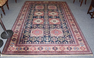 Lot 1160 - A Caucasian design carpet, the indigo field with two columns of panels containing hooked guls...
