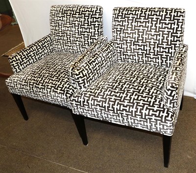 Lot 1253 - A pair of modern armchairs upholstered in a black and white geometric farbric, raised on...