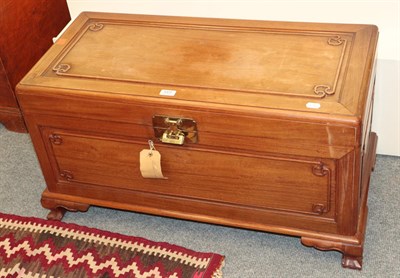 Lot 1377 - A Chinese carved camphor wood chest with brass clasp and padlock, raised on ball and claw supports