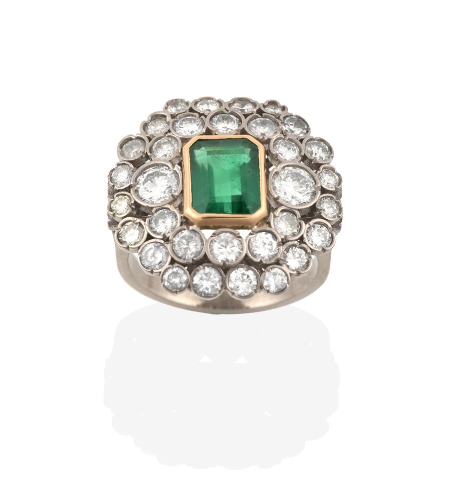 Lot 2022 - An Emerald and Diamond Ring, the emerald-cut emerald in a yellow rubbed over setting, within a...