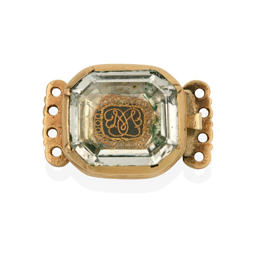 Lot 2030 - A Stuart Crystal Clasp, the emerald-cut rock crystal laid upon a hairwork and wirework plaque, with