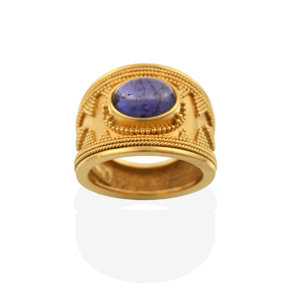 Lot 2053 - An Iolite Ring, possibly by Ilias Lalaounis, the central oval cabochon iolite in a yellow...