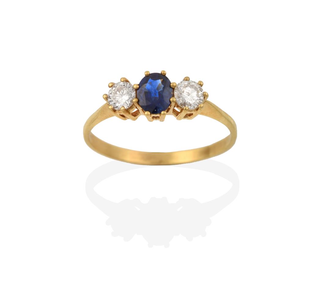 Lot 2063 - A Sapphire and Diamond Three Stone Ring, the oval cut sapphire flanked by round brilliant cut...