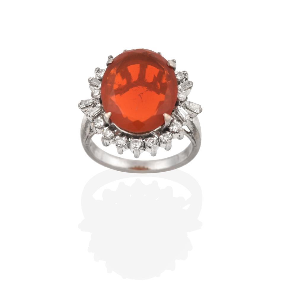 Lot 2064 - A Fire Opal and Diamond Cluster Ring, the oval cut fire opal within a border of eight-cut...