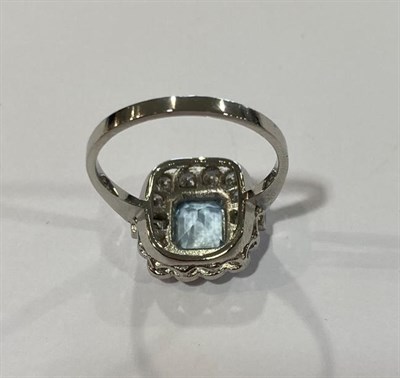 Lot 2065 - An Aquamarine and Diamond Cluster Ring, the emerald-cut aquamarine within a border of round...