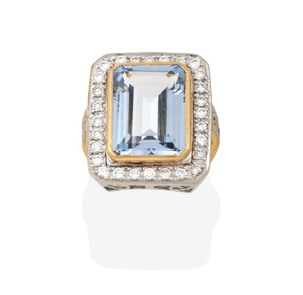 Lot 2076 - An Aquamarine and Diamond Cluster Ring, the emerald-cut aquamarine in a yellow millegrain...