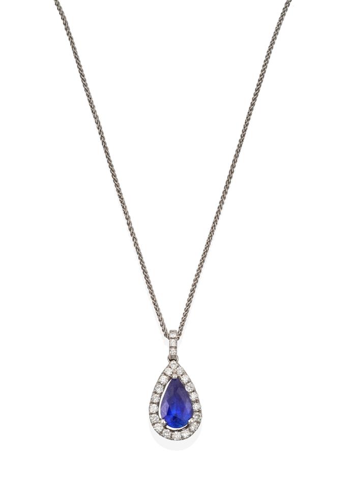 Lot 2079 - An 18 Carat White Gold Sapphire and Diamond Pendant on Chain, the pear shaped sapphire within a...