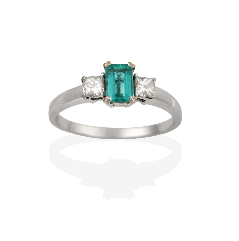Lot 2081 - An 18 Carat White Gold Emerald and Diamond Three Stone Ring, the emerald-cut emerald flanked by...