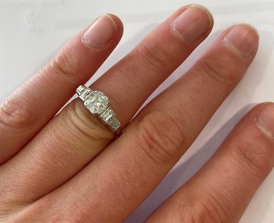 Lot 2097 - A Diamond Five Stone Ring, the central emerald-cut diamond flanked by graduated step cut...