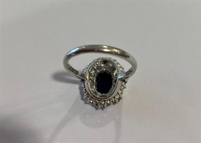 Lot 2114 - A Sapphire and Diamond Cluster Ring, the oval cut sapphire within a border of old cut diamonds,...