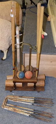 Lot 1087 - An early 20th century croquet set comprising four clubs, four balls on an oak stand with six hoops
