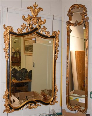 Lot 1220 - A reproduction gilt and black painted mirror, the shaped bevelled plate within leaf scroll...