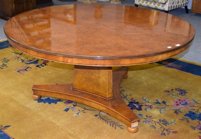 Lot 1292 - A reproduction inlaid burr walnut circular pedestal dining table raised on a massive triform...