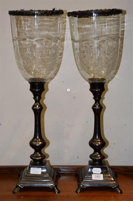 Lot 1303 - A pair of silvered metal candle sticks with etched glass hurricane shades, 62cm high