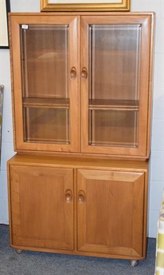 Lot 1307 - An Ercol light oak bookcase, glazed twin door upper section above base with twin cupboard...