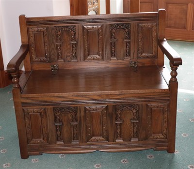 Lot 1402 - An Old Charm box settle, the back panel with moulded arch panels above a hinged seat with...