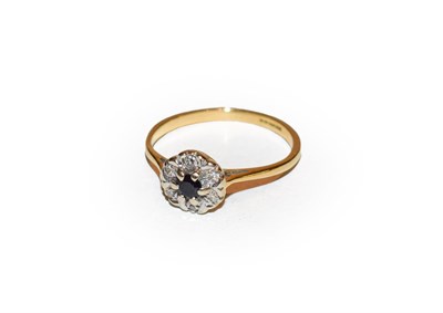 Lot 154 - An 18 carat gold sapphire and diamond cluster ring, the round cut sapphire within a border of...