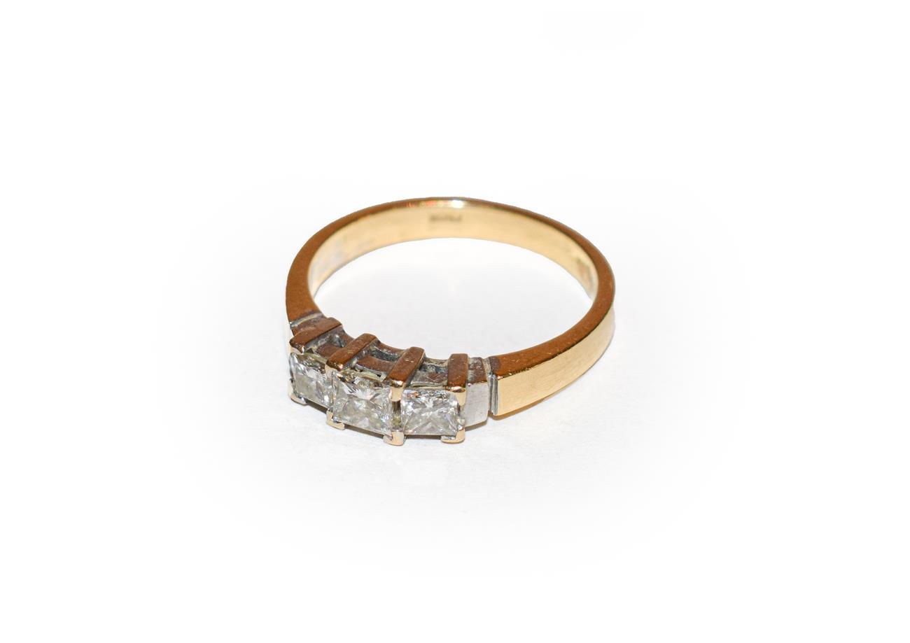 Lot 157 - A diamond three stone ring, the graduated princess cut diamonds in white claw settings, to a yellow