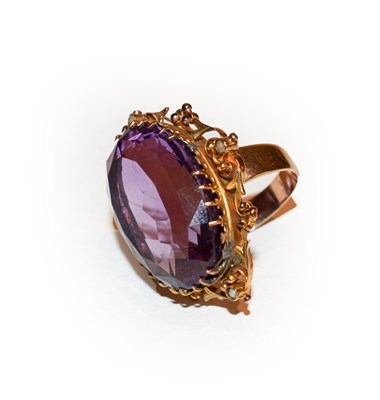 Lot 162 - An amethyst ring, the oval cut amethyst in a yellow claw setting, within a scroll border,...