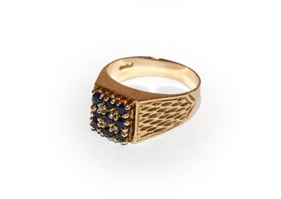 Lot 165 - A 9 carat gold sapphire ring, the round cut sapphire cluster in yellow claw settings, to a textured