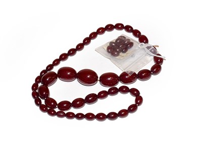 Lot 173 - A cherry red amber bead necklace, length 66cm with ten loose amber beads