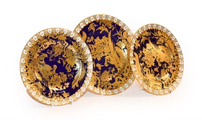 Lot 332 - Royal Crown Derby, a set of three cobalt blue and gilt plates decorated with exotic birds (3)